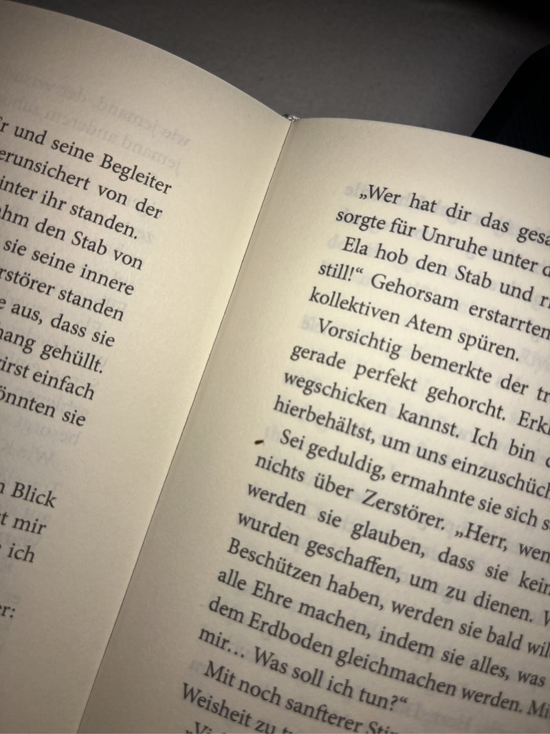 Ein kleiner Moderkäfer sitzt auf der bedruckten Seite eines offenen Buches. Die Aufnahme zeigt das Insekten-Exemplar aus der Nahperspektive.